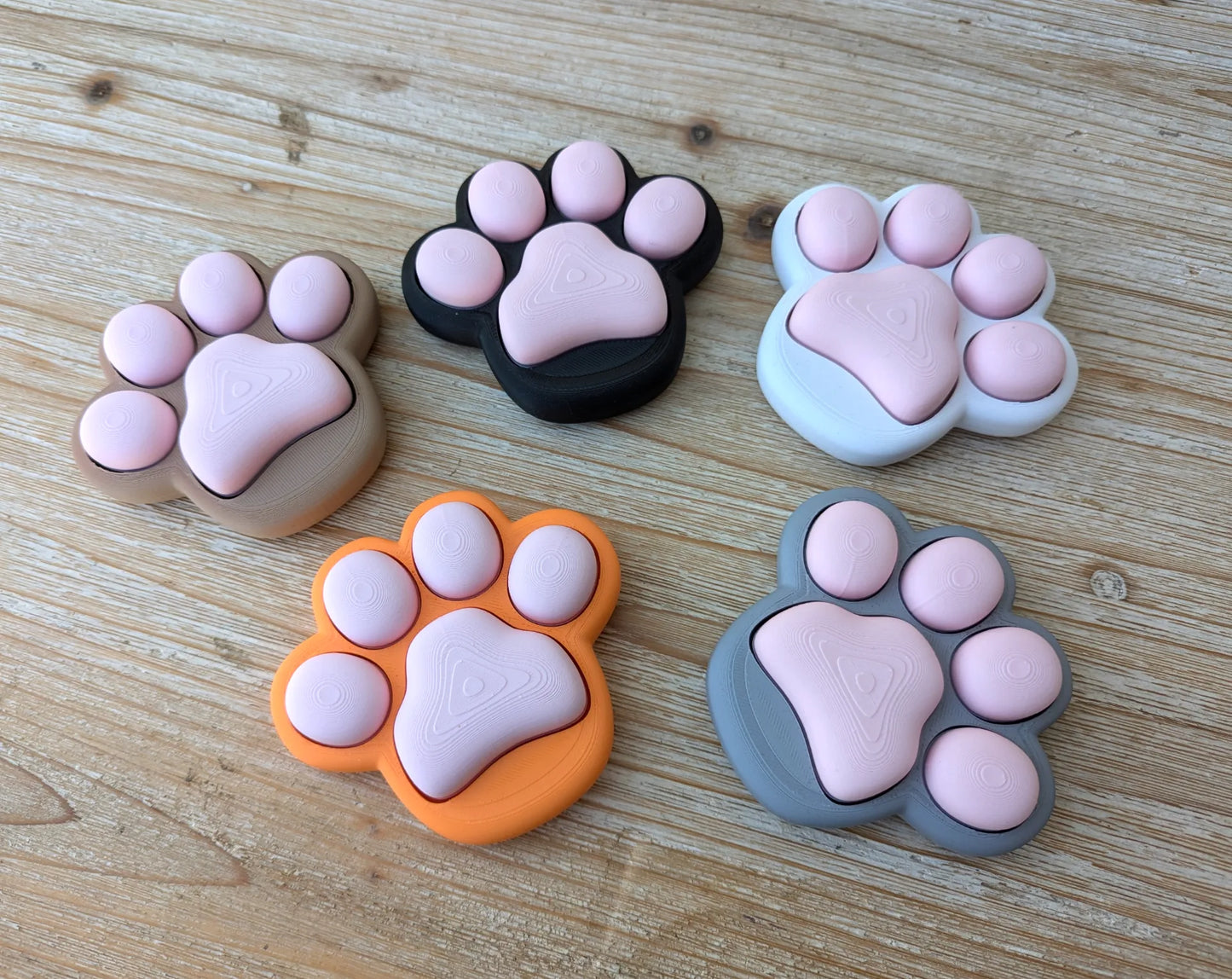 Patita Clicker Antiestrés impresa en 3D con diseño de huella de mascota para aliviar el estrés y mantener las manos ocupadas.