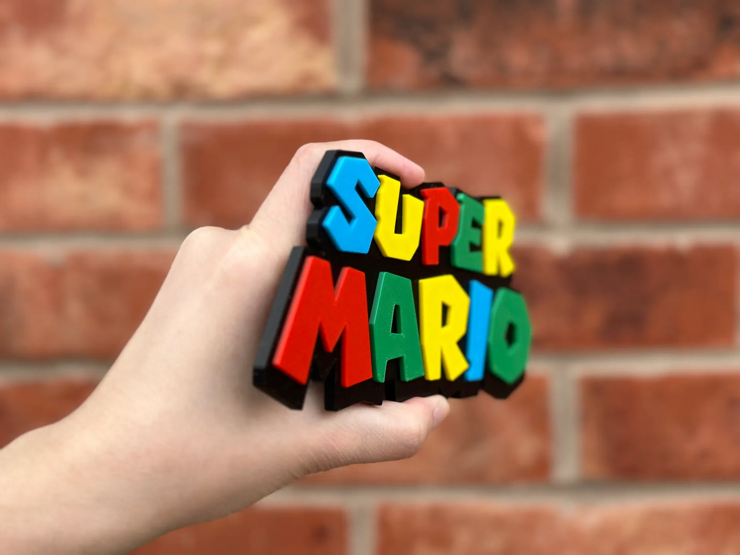 Logo 3D de Super Mario con acabado mate y gran nivel de detalle para decoración de vitrinas, escritorios y zonas gaming.