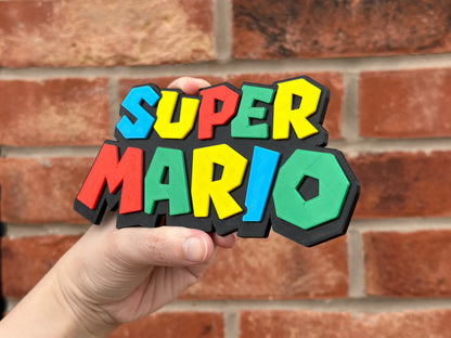 Logo 3D de Super Mario con acabado mate y gran nivel de detalle para decoración de vitrinas, escritorios y zonas gaming.