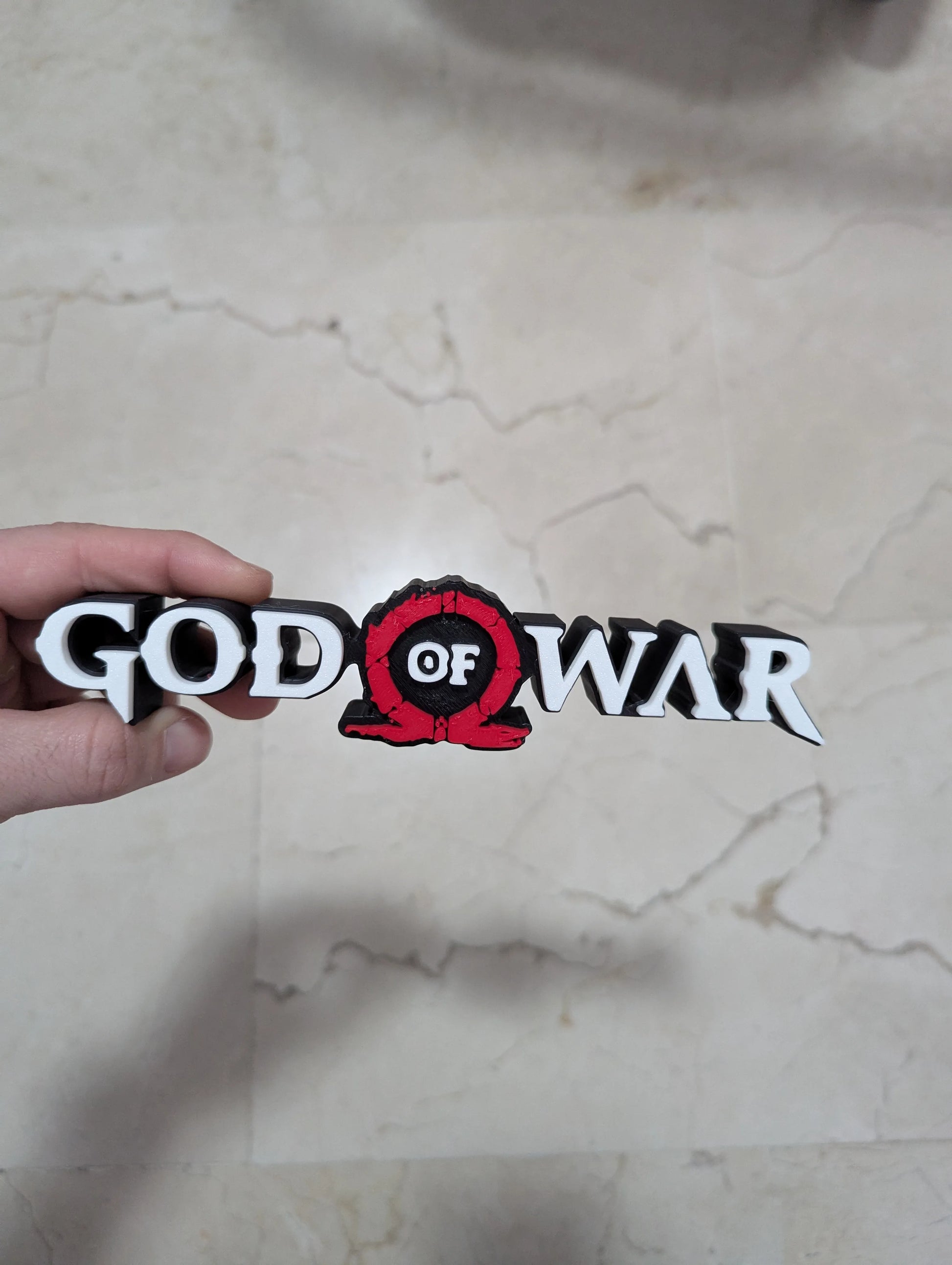 Logo 3D de God of War con acabado mate y gran nivel de detalle para decoración de vitrinas, escritorios y zonas gaming.